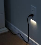 A Decora-style LED outlet cover plate mounted on a wall, giving gentle, diffused lighting at night.