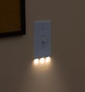 An LED toggle switch cover plate mounted on a wall, giving gentle, diffused illumination at night.