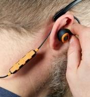 A man inserts an ISOtunes Pro 2.0 corded electronic hearing protector earbud into his ear