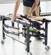 A man folding the mobile sawing table to a more compact size