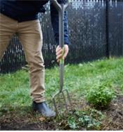 A man digs in a garden using the Radius Ergonomic Stainless-Steel Digging Fork