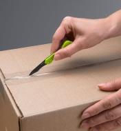 Slicing through packing tape on a cardboard box using the Keychain Safety Cutter