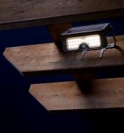 Motion-sensing solar LED floodlight mounted on a pergola overhead