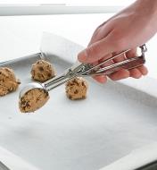 Scooping cookie dough onto a cookie sheet lined with parchment paper