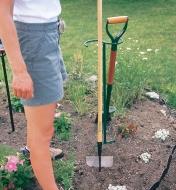 A woman leans a hoe against a Macgregor Tool Butler installed in a garden