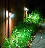 Motion-Sensing Solar LED Lights mounted on a fence, illuminated at night