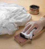 Applying stain to a strip of wood with an absorbent cotton wipe