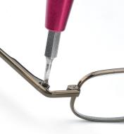 Le tournevis de 3 1/8 po en aluminium vissant une petite vis sur la monture d'une paire de lunettes