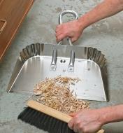 Sweeping wood shavings into an Aluminum Dustpan