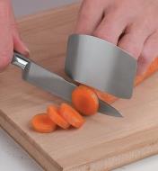 Personne utilisant un protège-doigts pour couper des carottes