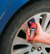 Personne vérifiant la pression d'un pneu à l'aide d'un manomètre numérique