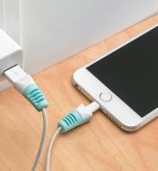 An iPhone plugged into a charger with cable savers on either end of the cable