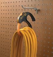 Looped electrical cord secured by a large CableClamp, hanging from a hook on a pegboard