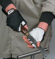 A person wearing Anti-Vibration Gloves holds a turning scraper on a tool rest