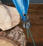 Aluminum CamJam Cord Tightener holding a tarp over a woodpile