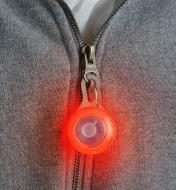 Red Carabiner Light attached to a sweatshirt zipper