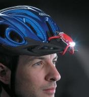 A man wears a Red BugLit LED Micro-Light on the peak of a bike helmet