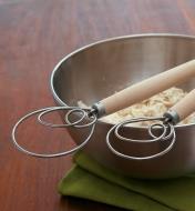 Both sizes of Dough Whisks lying across a mixing bowl