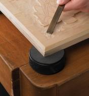 Grip disc attached to a hockey puck, used as a work standoff under a relief carving