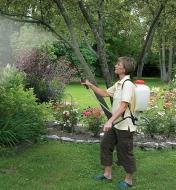 A woman uses a Backpack Sprayer to spray a garden