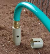 Deep Drip Watering Spike inserted into the ground, attached to a garden hose
