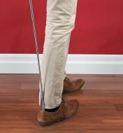 A person puts on a shoe with the help of the Extendable Shoehorn