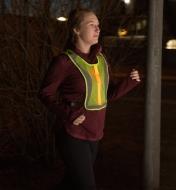A woman wearing the High-Visibility LED Vest runs in the dark