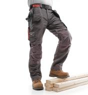 A man poses in Gray Medium-Weight Pants with his foot on a stack of lumber