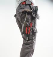 Side view of gray pants with various tools in the loops and pockets