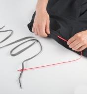 A loop on the tail of the Easy Threader holds the drawstring, while the threader is passed through the channel on the waistband of a bathing suit
