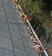 Gutter Brush installed in eavestrough with fallen leaves sitting on top