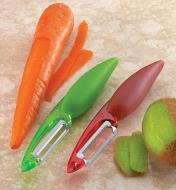 Set of two peelers on a counter beside carrot and kiwi that have just been peeled