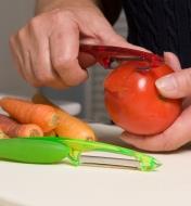 Personne pelant une tomate avec un éplucheur à lame dentelée