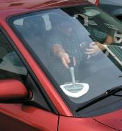 Using the Glass and Surface Cleaner to wash the inside corner of a car windshield