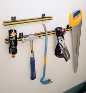 Both sizes of tool bar attached to a wall, with various hand tools clinging to the 24" size