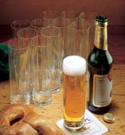 Douzaine de verres à bière Kölsch dont l'un est rempli de bière à côté d'une bouteille de bière et d'un bretzel