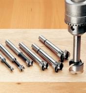 Set of 6 HSS Forstner bits lying on a board next to a drill press
