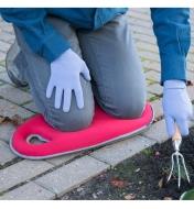 A person kneels on a Red Kneeling Pad while gardening