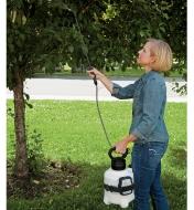 A woman sprays a tree using the Garden Sprayer