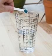 Personne versant de l'engrais dans un verre à mesurer rempli d'eau
