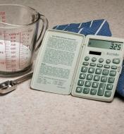 Calculatrice de cuisine Lee Valley posée sur un comptoir près d'une tasse et d'une cuillère à mesurer
