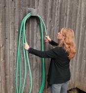 A woman loops a hose over the Hose Hanger