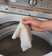 Personne déposant un essuie-tout réutilisable dans une machine à laver