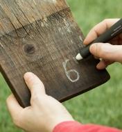 Drawing a number on dark wood with a Pica-Visor White Marking Crayon