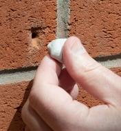Preparing to fill a hole in a brick wall with Epoxy Putty