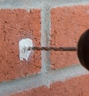 Drilling into cured Epoxy Putty filling a hole in a brick wall