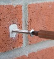 Screwing a fastener into cured Epoxy Putty filling a hole in a brick wall