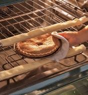 Removing a pie from an oven with oven guards attached to the racks