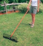 A woman uses a Power Rake with the handle turned sideways