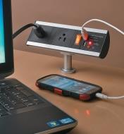 Cell phone and laptop plugged into a Stand-Off Power Bar installed in a desk